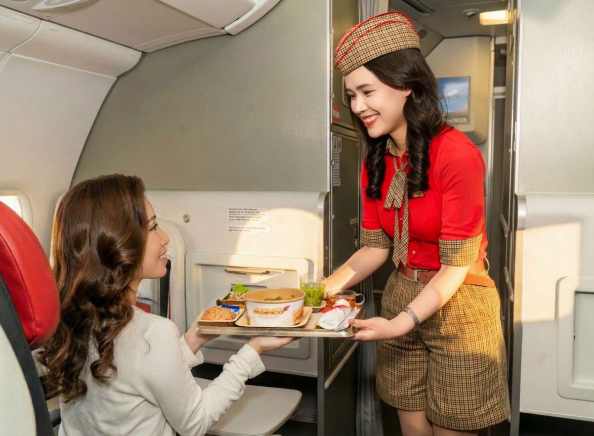 Tiếp viên mặc đồng phục Vietjet phục vụ suất ăn cho hành khách trên máy bay